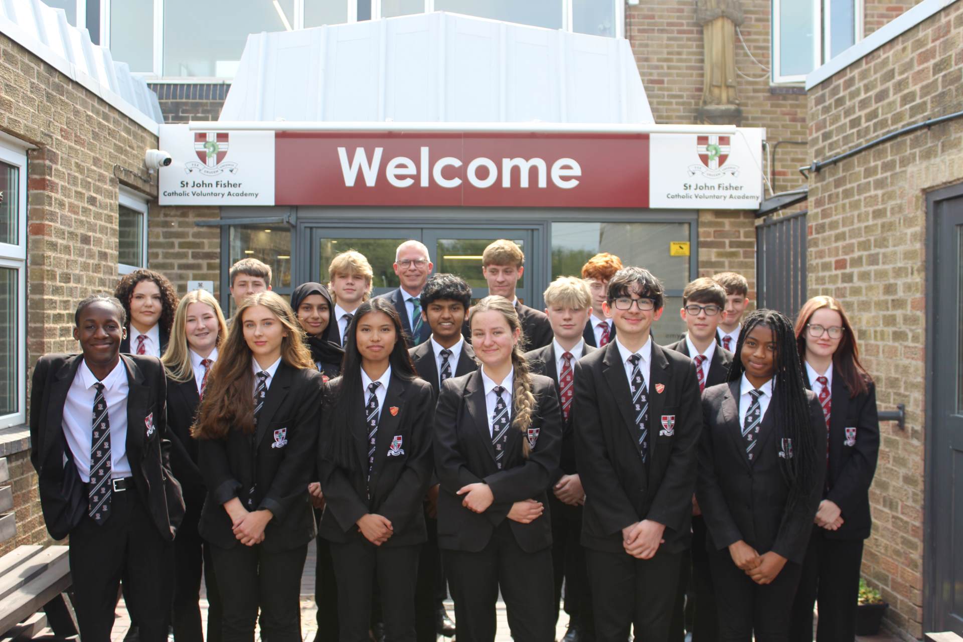 Headteacher Karl Mackey and selection of pupils standing proudly in the school entrance